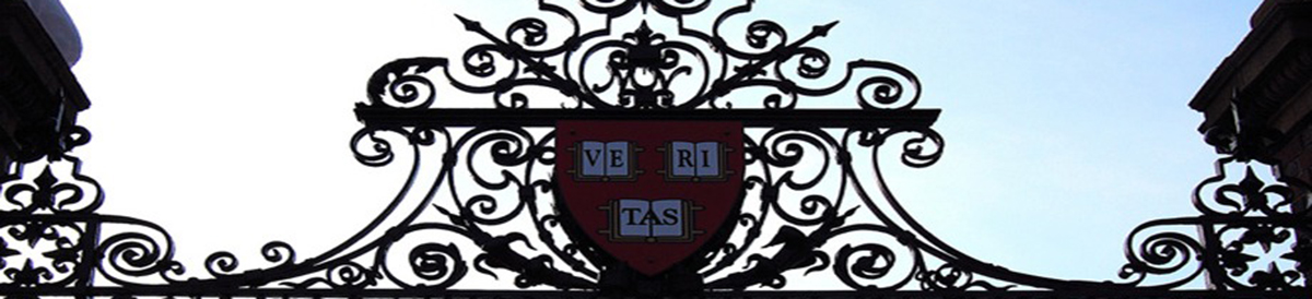 A closeup of the Harvard Gates decorated with the red Harvard Veritas shield
